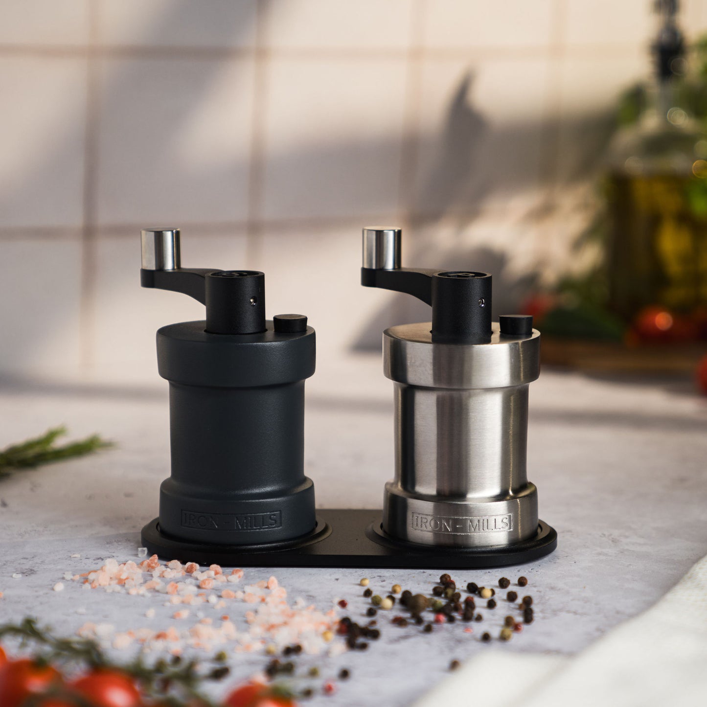 Iron-Mills anthracite grey and brushed stainless steel salt and pepper mills displayed on a mill rest in a premium setup