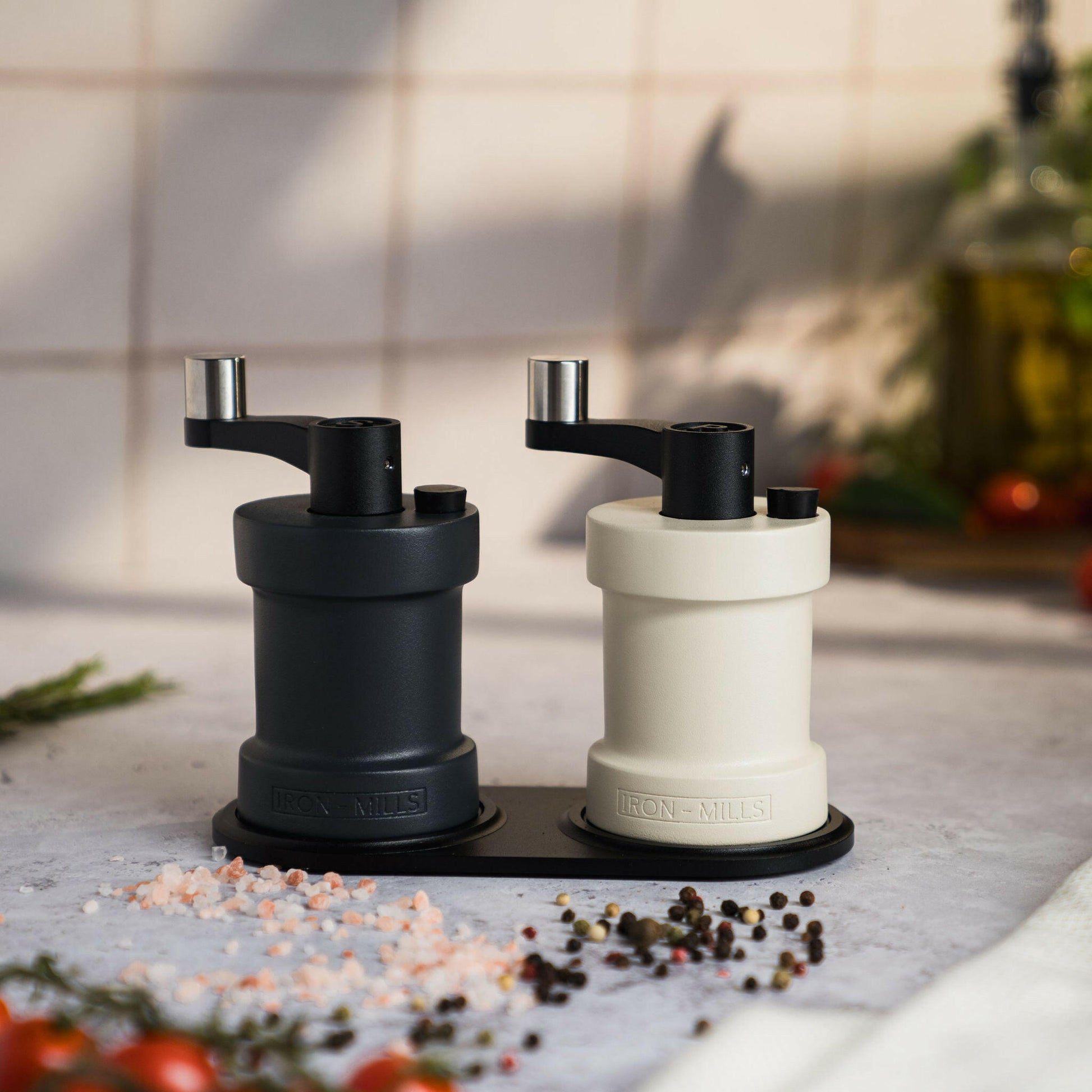 Iron-Mills anthracite grey and oyster white salt and pepper mills showcased on a sleek cast mill rest
