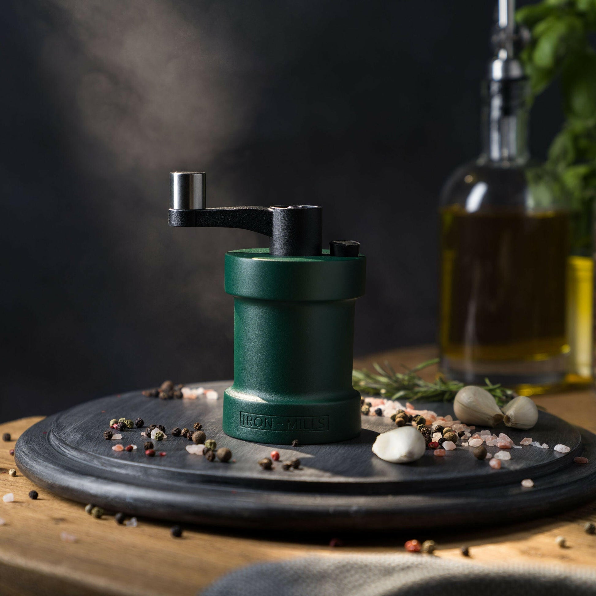 Iron-Mills ivy green salt mill on a chopping board in a fresh vibrant kitchen with salt and peppercorns