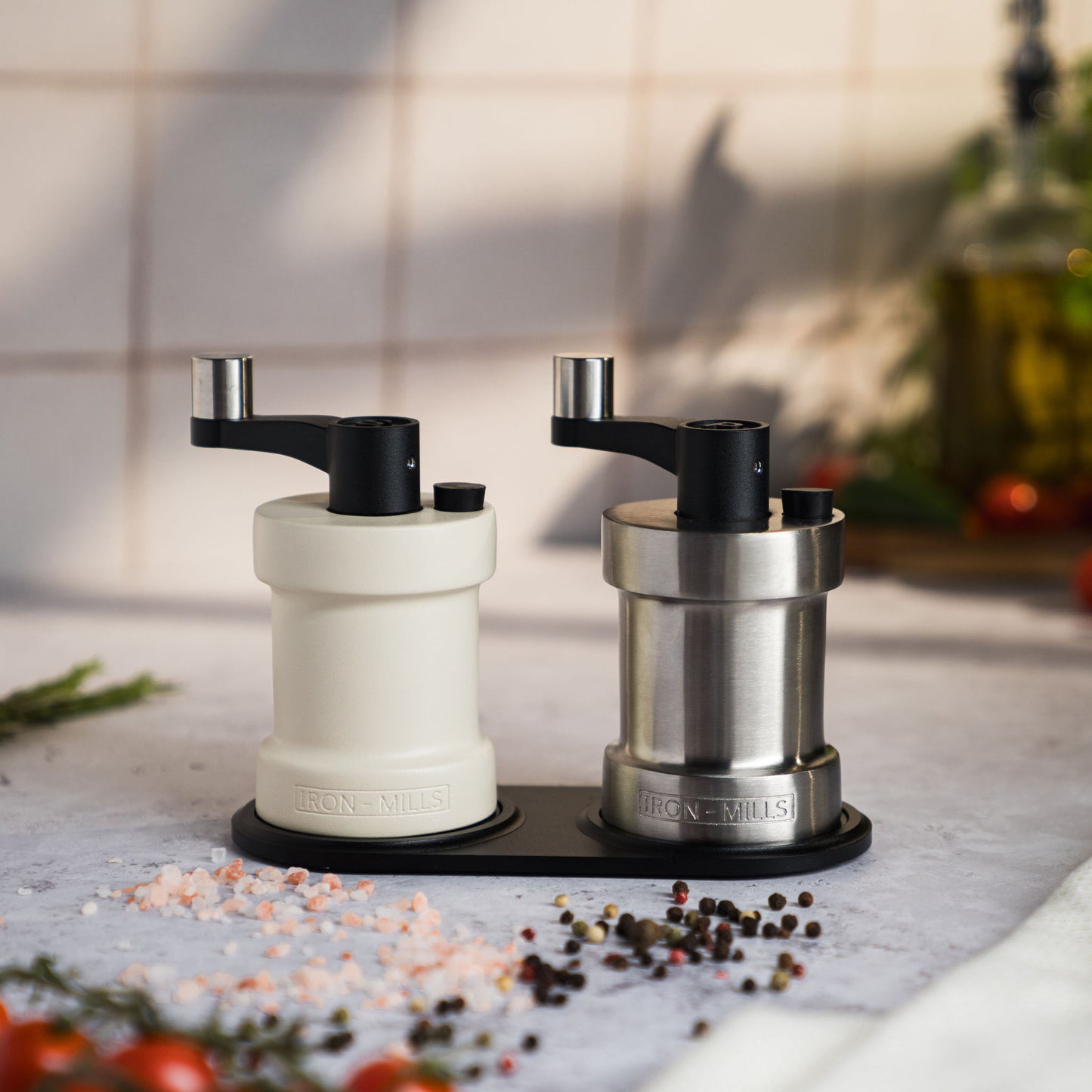 Iron-Mills oyster white and brushed stainless steel salt and pepper mills displayed on a classic mill rest with seasoning