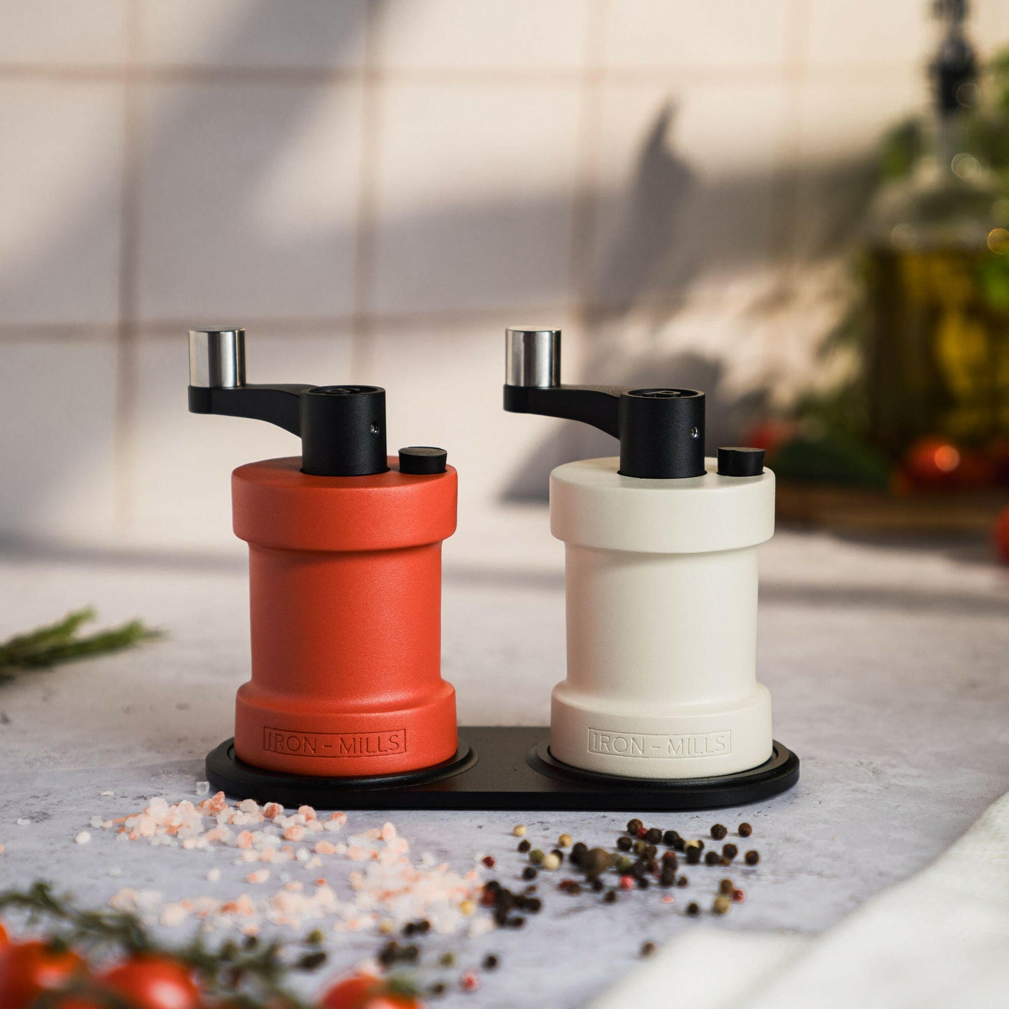 Iron-Mills oyster white and coral red salt and pepper mills placed on a minimalist mill rest for an elegant table display
