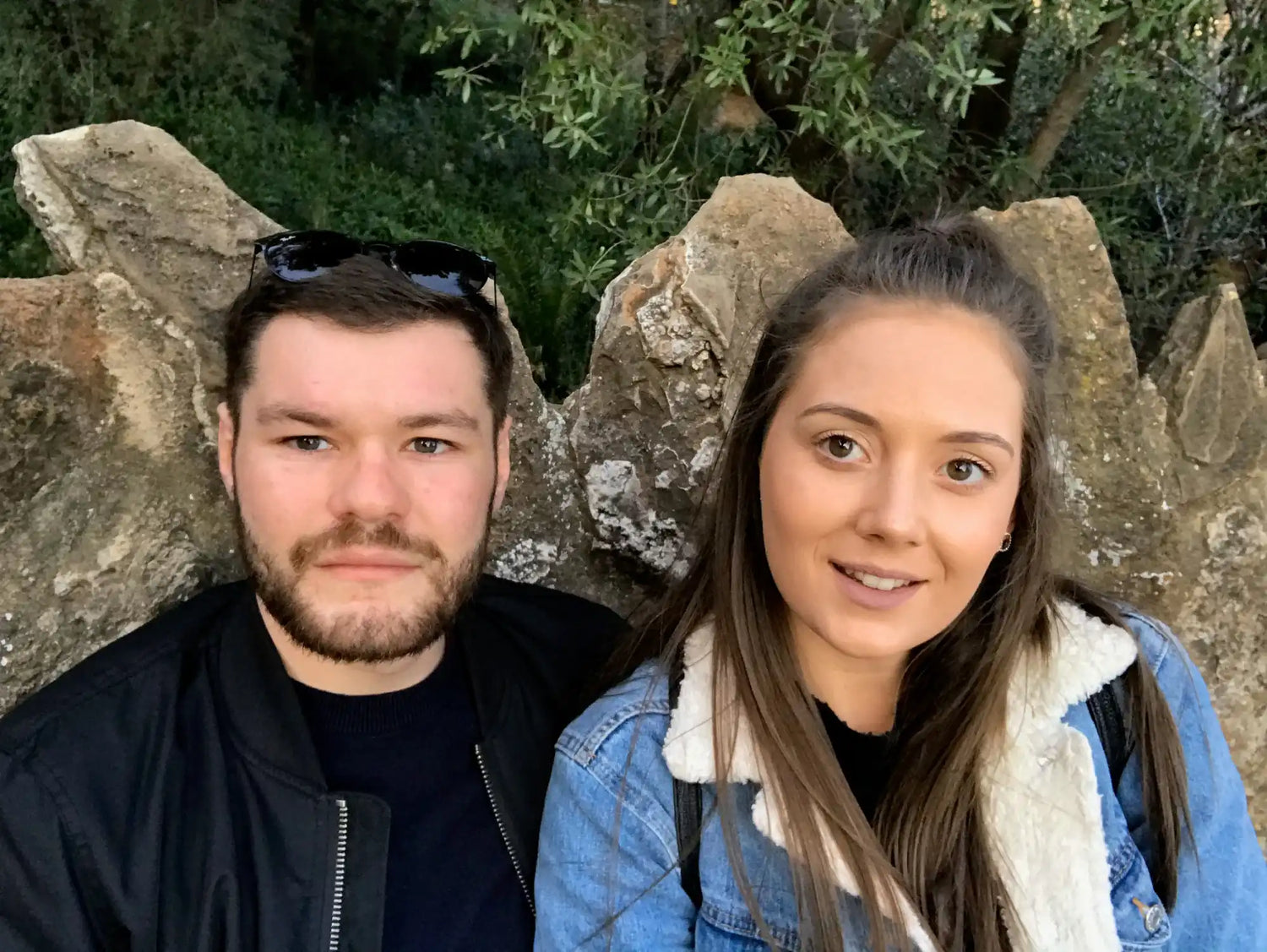 Two people taking a selfie together in front of a stone wall.